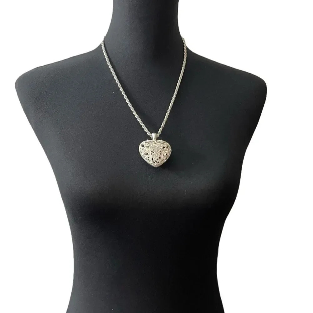 Silver colored heart locket necklace filled with rhinestones in the front side